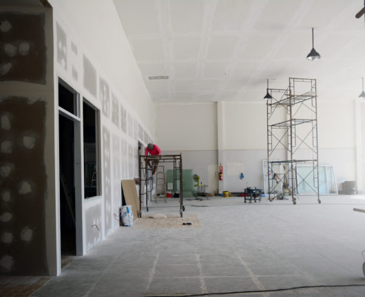 the iron scaffoldings on tile ground and the black lamp on  the ceiling with the labor while  renovation  the old office